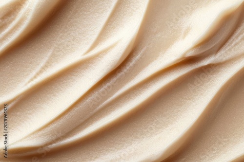 silky beige cosmetic cream close-up showing smooth flowing waves and glossy swirls, velvety texture evoking a luxurious calming and soothing skincare sensation