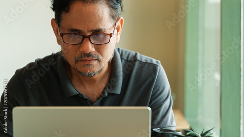 Vászonkép Focused mature businessman working on laptop in modern workspace, serious profes