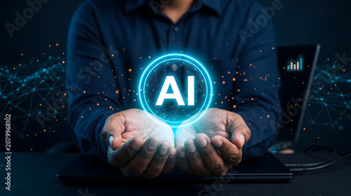 Man in Dark Blue Shirt Holding Glowing AI Symbol in Front of Laptop on Desk in Dark Room