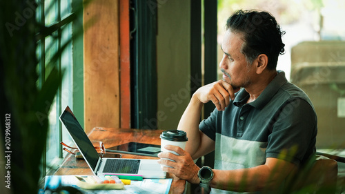 Senior Entrepreneur Reviewing Business Reports While Working in Coffee Shop