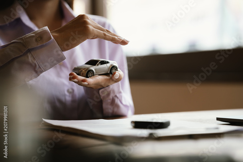 Foto Hands protecting a model car, symbolizing vehicle insurance, financial protection, ownership, and automotive security