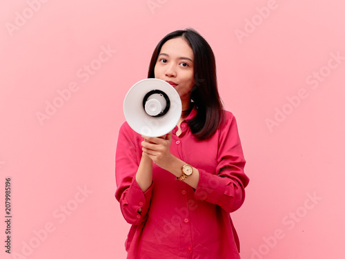 Konstfotografi A portrait of a young Asian woman holding a white megaphone to her mouth to make a loud announcement