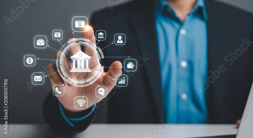 Man in business attire presenting a bank icon on his hand with various app icons around it on a desk.