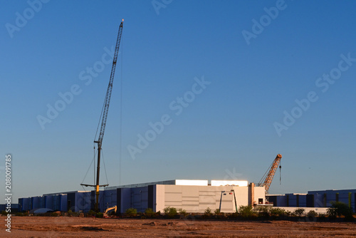 Large data center campus under construction with mobile cranes, prefabricated equipment modules, and utility infrastructure, representing digital infrastructure expansion and cloud computing developme
