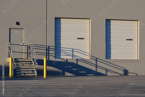 Loading dock doors with an accessible ramp and stairway at a commercial warehouse, representing industrial logistics, freight distribution, and warehouse infrastructure