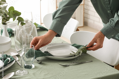 Canvas Print Person setting a green-themed dining table with white dishes