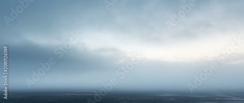 foggy seascape with calm dark ocean, low horizon and brooding overcast sky conveying solitude and melancholy