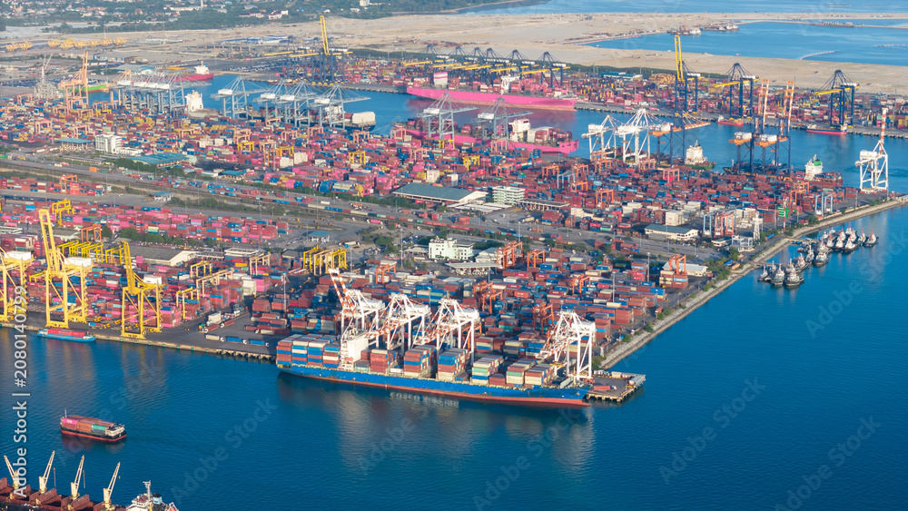 Fototapeta premium commercial port terminal with cargo ships, container stacks, gantry cranes, storage warehouses, and large car parking lots facilitating global maritime trade and logistics supply chain.