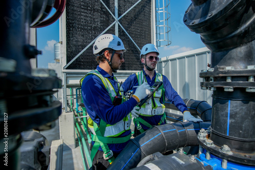 HVAC Engineers Inspecting Rooftop Cooling Tower. Industrial Maintenance Operation.