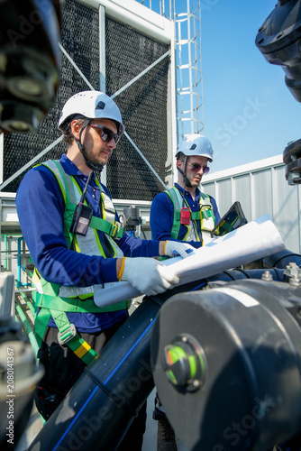 HVAC Engineers Inspecting Rooftop Cooling Tower. Industrial Maintenance Operation.