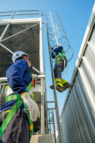 HVAC Engineer Ascending Cooling Tower Ladder. Rooftop Maintenance Work. Professional Industrial Inspection.
