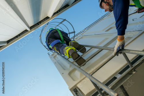 HVAC Engineer Ascending Cooling Tower Ladder. Rooftop Maintenance Work. Professional Industrial Inspection.