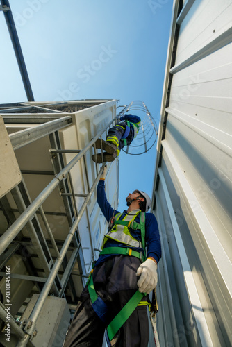 HVAC technicians perform cooling tower inspection. Rooftop maintenance, safety gear worn, industry professionals.