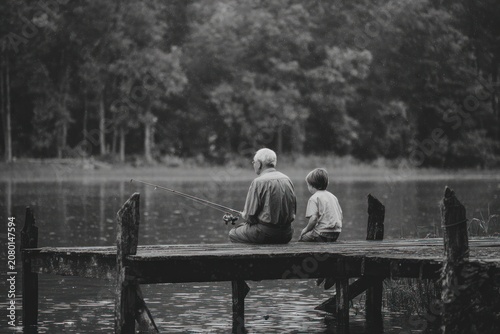 Elderly man and young boy fishing on a dock