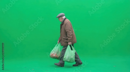Elderly man walking with grocery bags on green screen