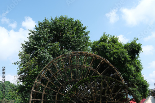 Fotografie Old wooden water wheel in a green garden