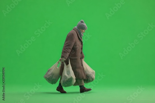Elderly person in brown coat, carrying bags