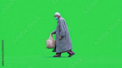Elderly person in gray coat, face mask, carrying grocery bag, walking on green screen