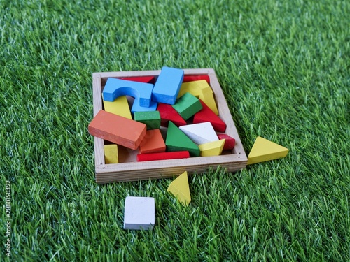 Detailed close-up of a child's educational wooden puzzle toy set placed outdoors on synthetic turf.