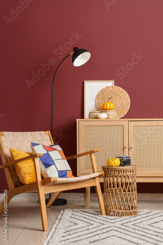 Interior of living room with wooden commode, armchair and pumpkins