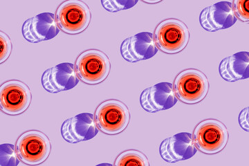 Pattern of glasses of red liqueur against pink background