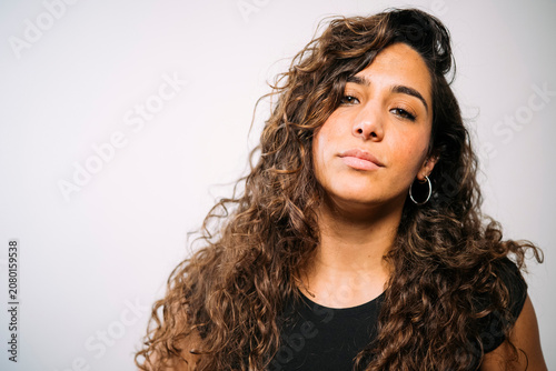 Young adult woman posing with curly hair and hoop earrings