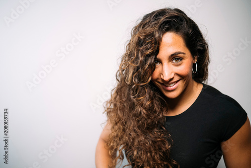 Smiling young adult woman with long curly hair