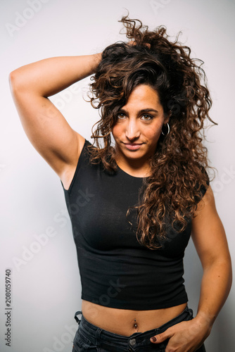 Young adult woman posing with confident expression and curly hair