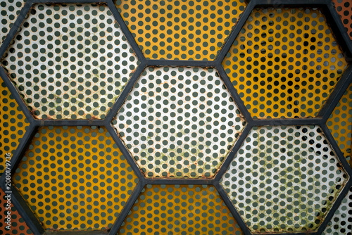 Geometric pattern of honeycomb cells filled with colorful metal. Abstract shapes form a textured mosaic