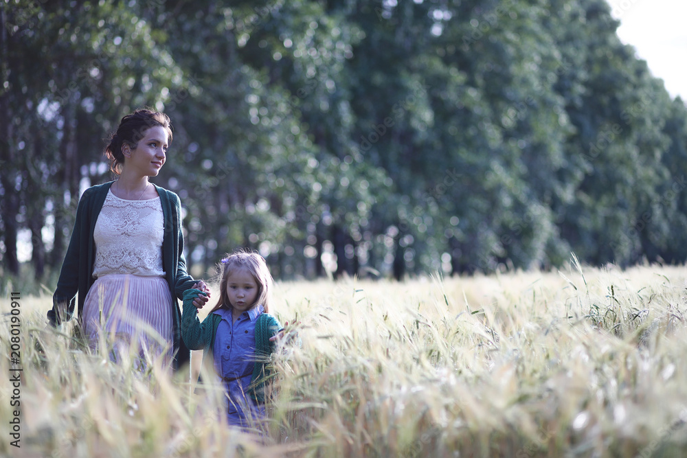 Fototapeta premium A young mother walk in wheat fields