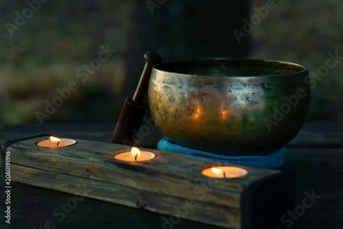 Valokuva Tibetan singing bowl with mallet sitting on a cushion, next to a wooden candle h