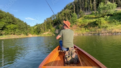 Rear view of fisherman sitting in a canoe and fishing on a freshwater lake