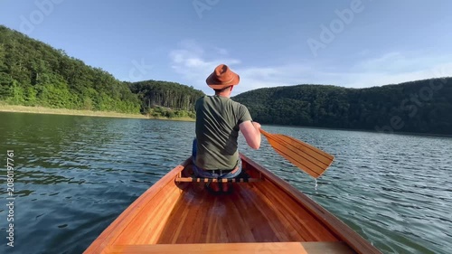 Rear view of man paddling a canoe on a calm freshwater lake