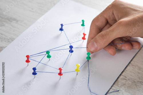 Man showing network connection with a push pins and thread.