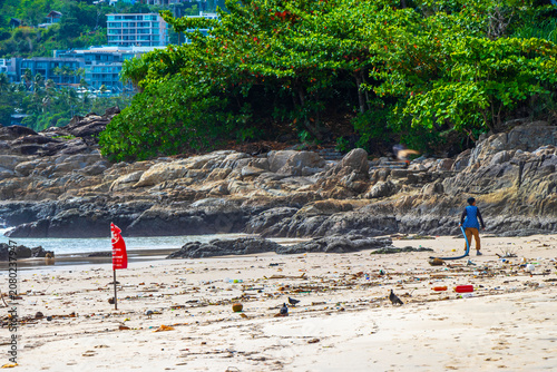Red warning flag above polluted tropical beach with dangerous ocean debris Thailand.