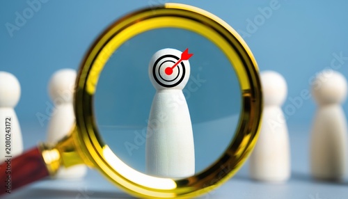 Magnifying glass focusing on a wooden figure with a target symbol