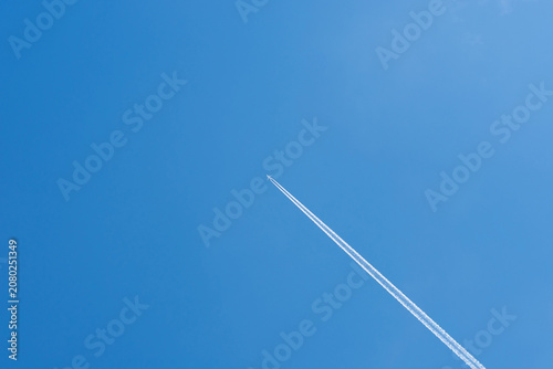 A jet plane and its contrail against the sky, photographed from the ground