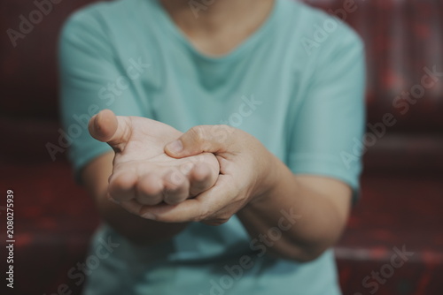 Fotografie A middle-aged woman, experiencing body aches, sits on a sofa receiving a massage to relieve muscle tension and improve her condition