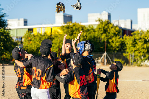 Canvas Print Young baseball players huddling and cheering after winning a game, showing camar