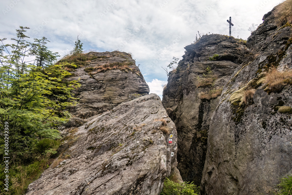Fototapeta premium Summit cross on the Rauchröhren rock formation along Kaitersberg ridge in the Bavarian Forest, Germany.
