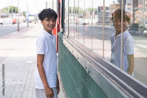 Foto Handsome teenage boy shopping on a commercial street, with the reflection of a shop or entertainment venue visible