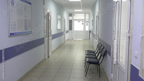 Hospital corridor with chairs and a door leading to patient wards. Clean medical facility interior with modern healthcare infrastructure. Concept of hospital environment, patient care, healthcare