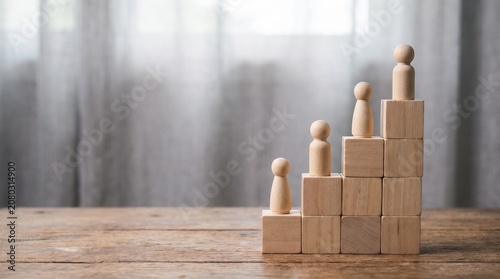 Wooden peg figures on a staircase of wooden blocks representing career growth, success, and business development.