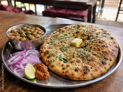  Amritsari Kulcha rellena con mantequilla, acompañada de chole, cebolla morada, limón y chutney.