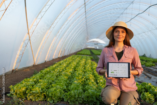 Farmer in greenhouse holding tablet with data about lettuce cultivation