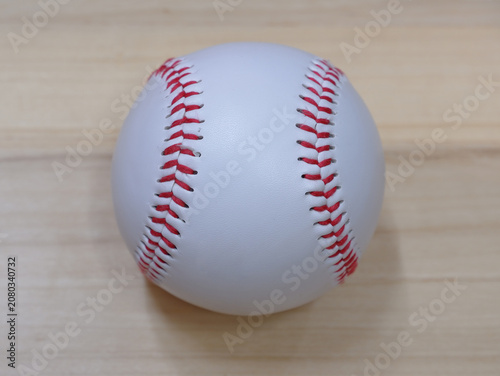 A white baseball with red stitching placed on a wooden background