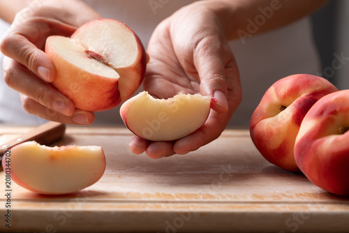 Bild auf Leinwand Woman hands holding a sliced fresh white peach, ready to eat