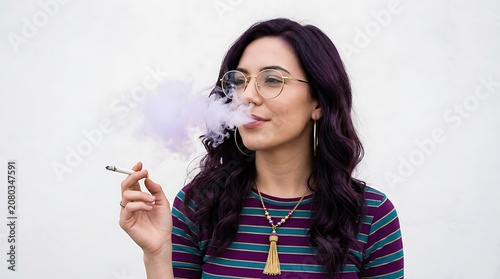 A person exhaling smoke from a cigarette in a neutral toned indoor environment with a calm expression.