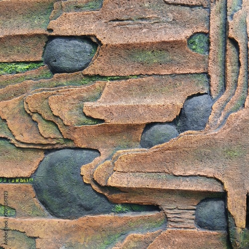 Textured abstract stone wall with layered natural rock and green moss
