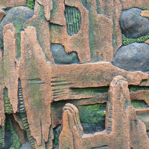 Textured stone wall with moss relief sculpture in a garden setting